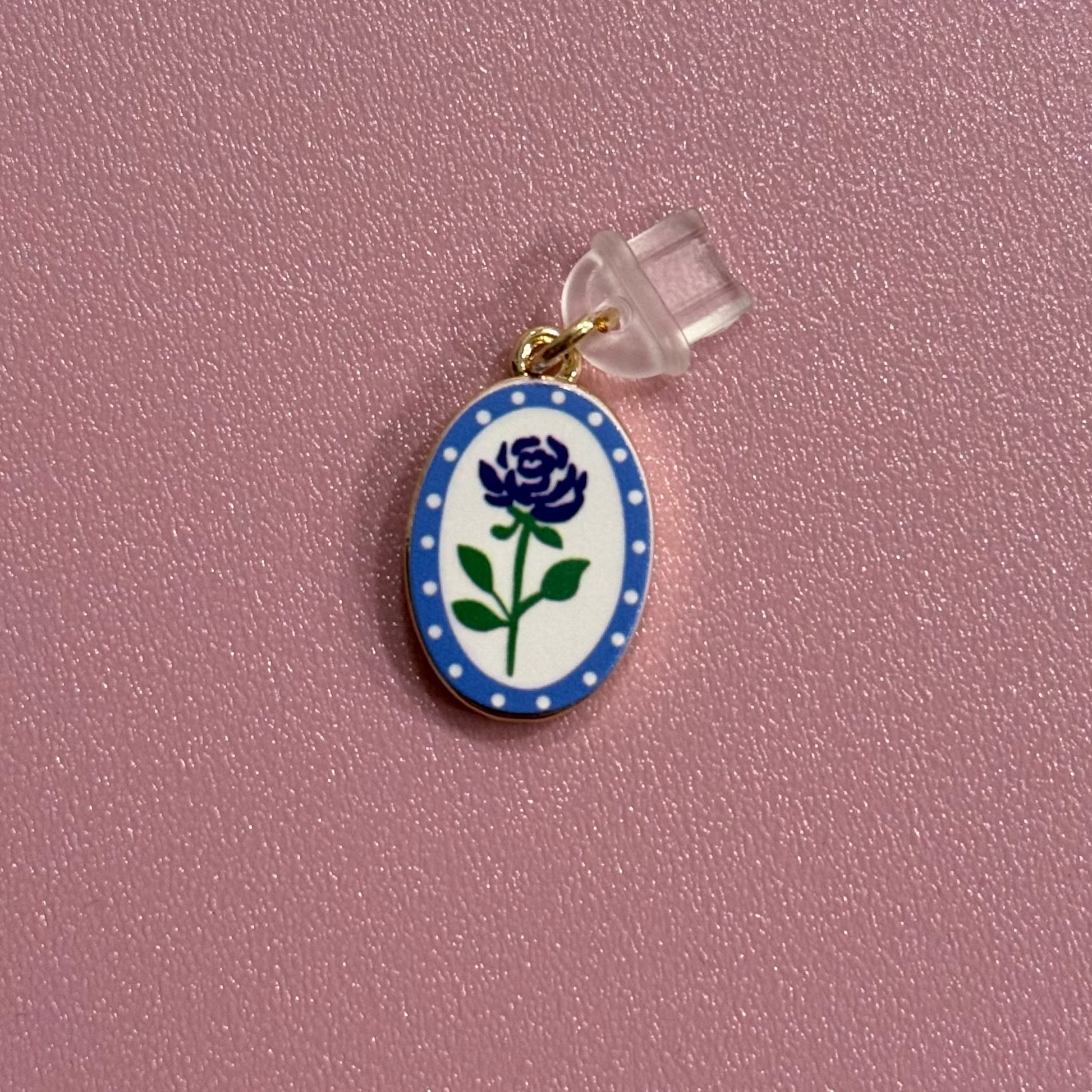 Small oval charm with a blue flower design on a pink background