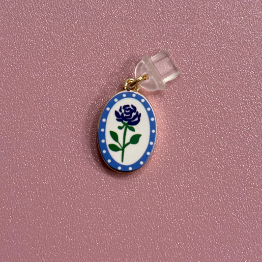 Small oval charm with a blue flower design on a pink background