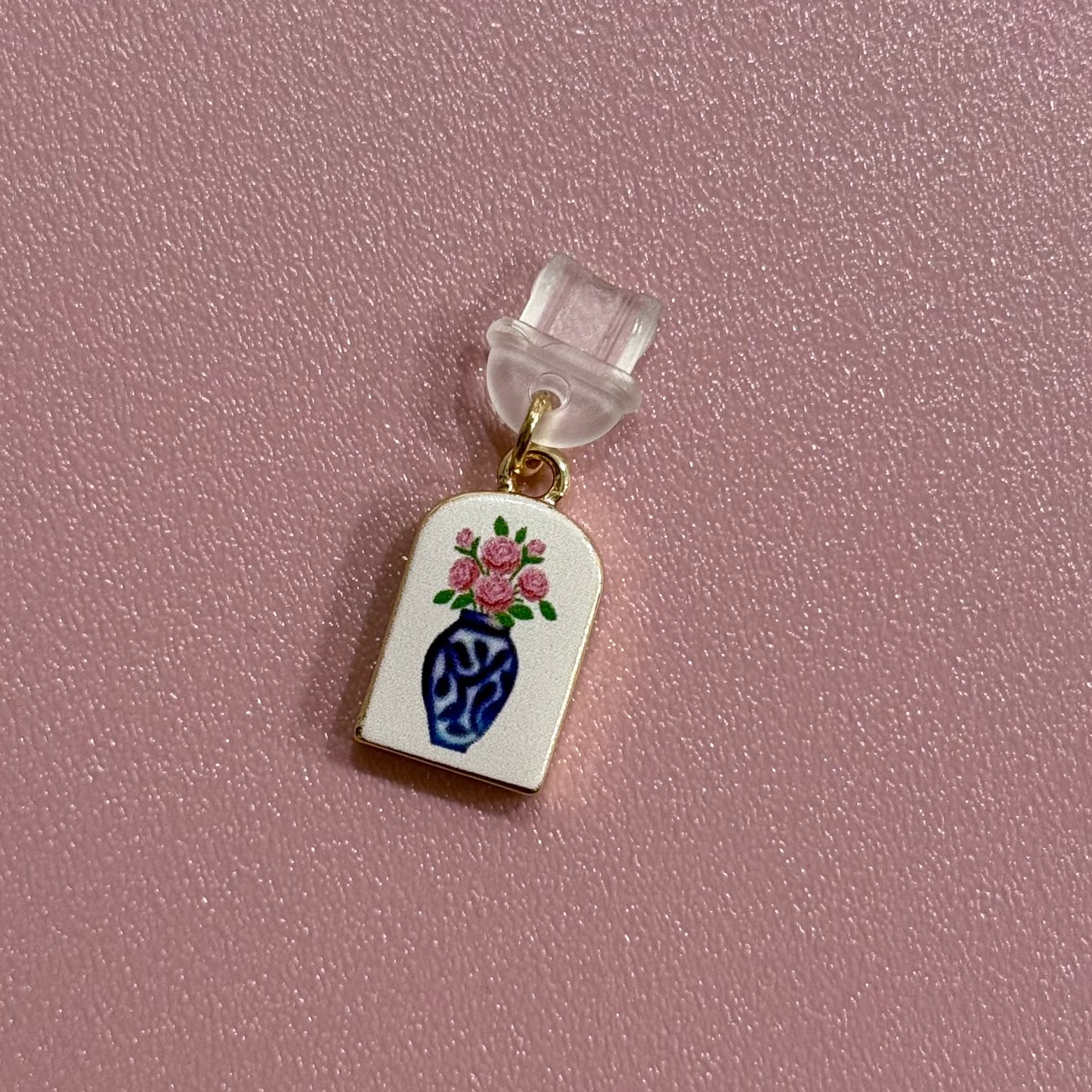 Small decorative charm with a floral design on a pink background
