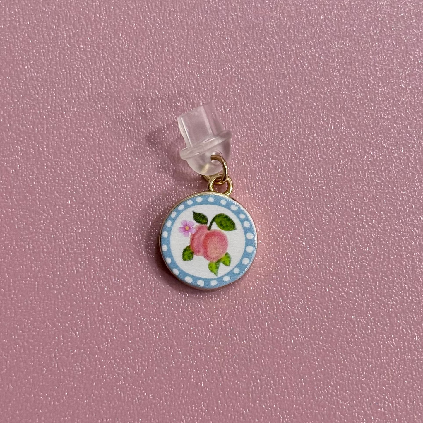 Small round charm with peach design on a pink background