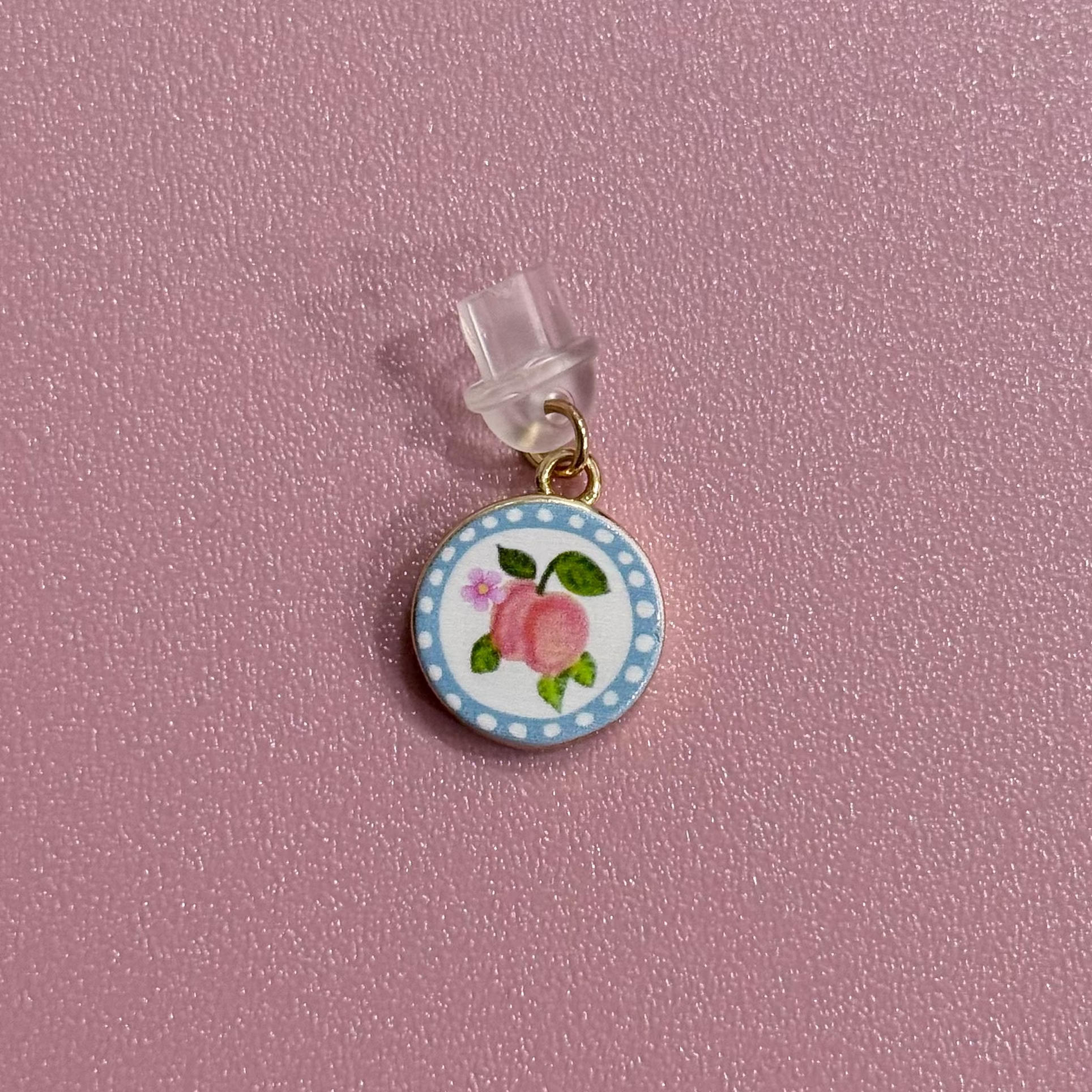 Small round charm with peach design on a pink background