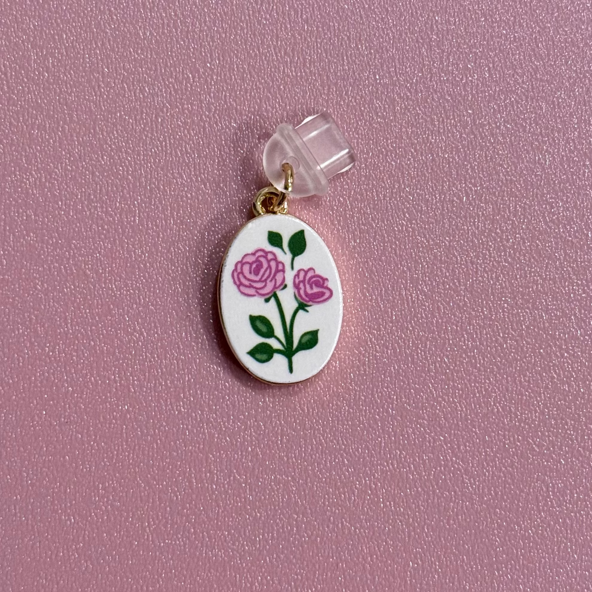 Small oval charm with double rose design on a pink background